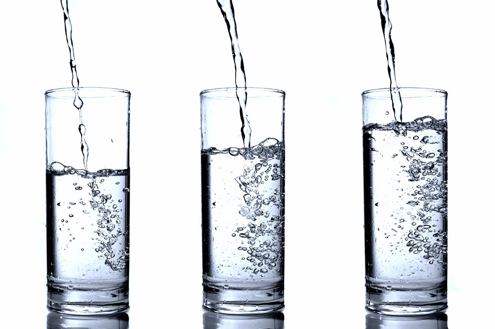 Image of water pouring into three different glasses
