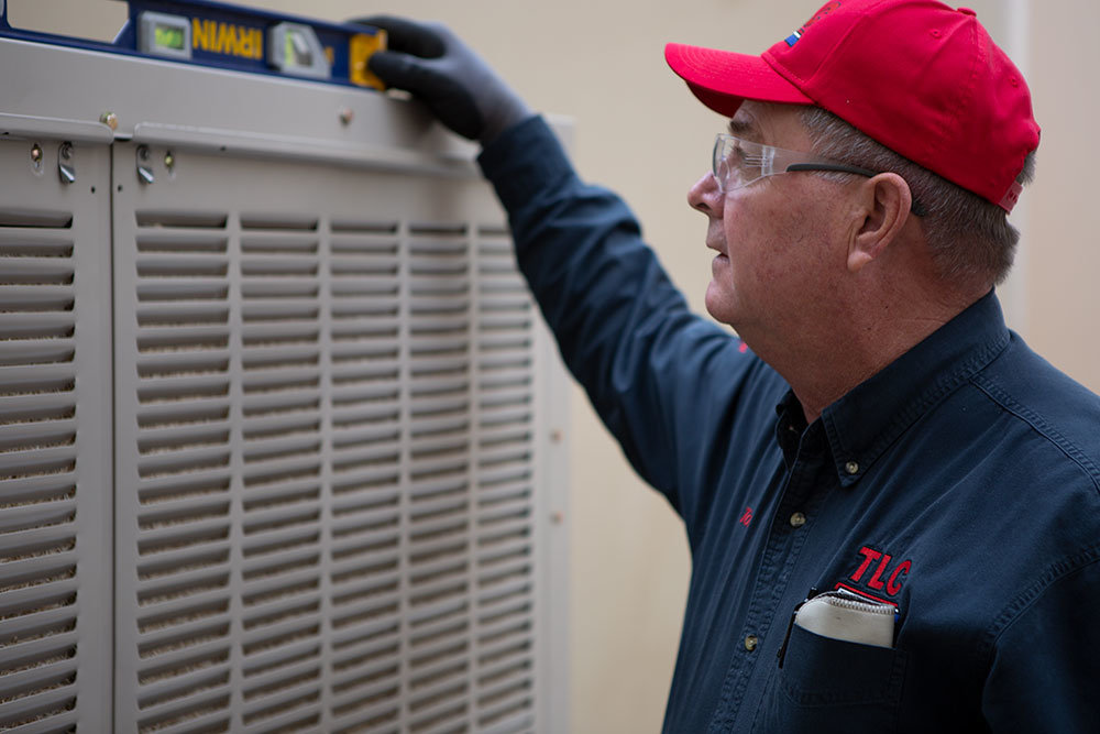 Image of a TLC employee with a level on top of a swamp cooler