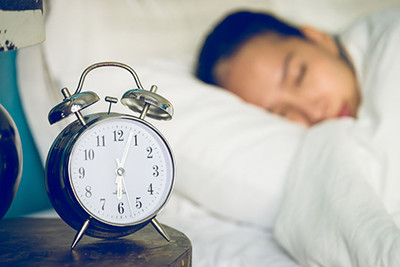 Image of someone sleeping by an alarm clock